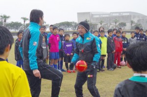 ボールトラップ時の体の使い方を指導する（左から）平瀬さんと遠藤さん＝２７日、奄美市笠利町の太陽が丘運動公園陸上競技場