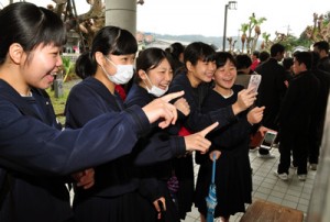 自分の番号を確認し、友人と喜び合う受験生たち＝１６日、奄美市名瀬の県立大島高校