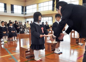 愛島校長から教科書を受け取り、笑顔の新入生＝６日、大和村の今里小学校