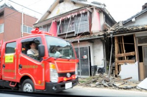 損壊した家屋の前を消防車が通る＝１８日午後５時５０分ごろ、氷川町