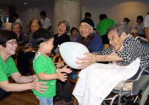 赤ちゃん先生と触れ合い、笑顔を見せる入所者ら＝１１日、奄美市名瀬