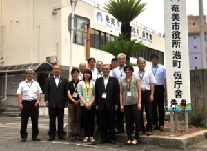 港町の仮庁舎前で部署移転をＰＲする朝山市長と職員ら＝１６日、奄美市名瀬港町