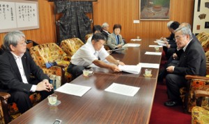 朝山毅市長（右）に自衛隊の誘致撤回を要望する住民グループのメンバー＝１７日、奄美市役所