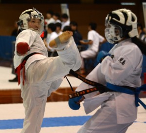 【空手女子団体組手】決勝リーグで明桜館の選手に蹴りを繰り出す大島の選手（左）＝７日、県体育館