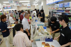 レジに並んだ買い物客の対応に追われる店員ら＝１５日午前７時１０分ごろ、奄美市