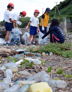 海岸のごみを集める円小児童と海保職員＝１１日、龍郷町円海岸