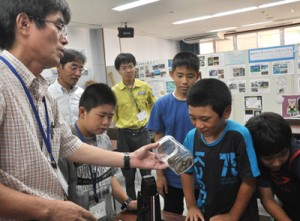 子ハブの入った容器を興味津々で観察する児童ら＝１９日、瀬戸内町立図書館・郷土館