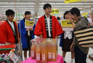 買い物客にオリジナルリキュールの説明をする奄美高校の生徒たち＝２４日、龍郷町