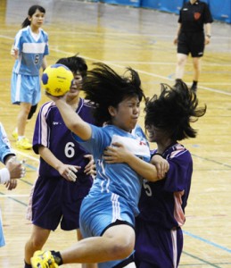 【ハンドボール女子決勝リーグ・大島―国分】相手ディフェンスを引きずりながらもゴールを狙う大島の元愛樹（３年）＝１１日、鹿児島アリーナ