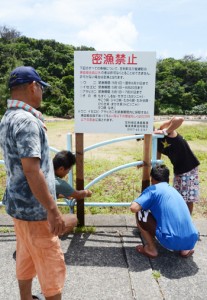 立て看板の設置作業をする笠利地区漁業集落メンバー＝１１日、奄美市笠利町