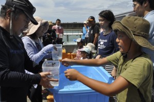 サンゴ株をダイバー（左側）に引き渡す出資者と、サンゴ株＝１６日、知名町沖泊漁港