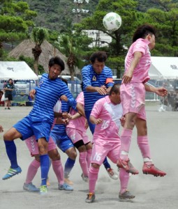 【サッカー予選】ゴール前で競り合う和泊と大和の選手＝１６日、龍郷町中央グラウンド  