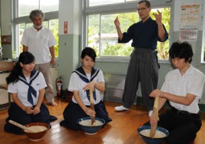 棚橋さん（右奥）の指導ですりゴマ作りを体験する生徒ら＝９日、瀬戸内町の俵中学校