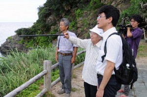 大島さん（左から２番目）の案内で遺体を埋めた場所を確認する調査団メンバー＝２５日、宇検村の船越海岸