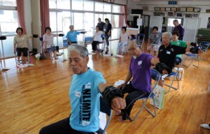 いきいきどぅくさ体操教室で、歌に合わせてゆっくりと腕を上げる参加者＝６月２３日、宇検村芦検