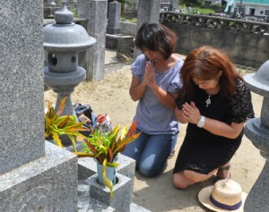 墓前で手を合わせて先祖の霊を迎える住民＝１３日、徳之島町