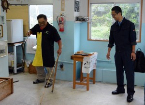 本山さん（左）からハブの退治法を学ぶ奄美署員＝７日、奄美観光ハブセンター