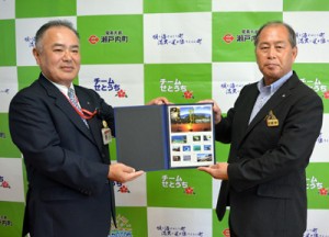 記念切手を受け取る鎌田町長と川畑局長（写真右から）と瀬戸内町制施行６０周年を記念のオリジナル切手シート＝２６日、町役場