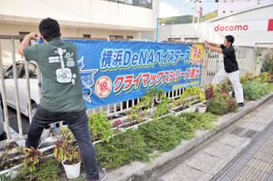 横浜ＤｅＮＡベイスターズのクライマックスシリーズ出場を祝う横断幕を設置する職員＝３０日、奄美市役所の仮庁舎