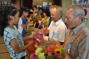 敬老会１００回記念の孫の手を贈る子どもら＝１８日、知名町瀬利覚