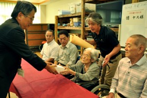 １００歳の長寿祝い品を受け取る徳ヤスさん（右から２人目）＝１４日、龍郷町　