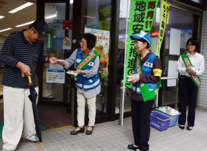 街頭でチラシを配る奄美署員と地域安全安全モニター＝１４日、奄美市名瀬港町