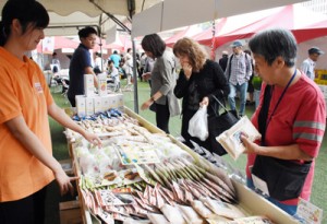 奄美産の商品を手に取る買い物客＝１２日、鹿児島市の鹿児島中央駅アミュ広場