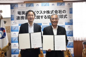 協定を結んだ朝山市長（右）と古俣社長＝７日、奄美市役所