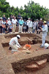 煙突と思われる遺構などが出土した久慈白糖工場跡（上）。工場跡から出土したアルファベッドの刻印のある英国製レンガ