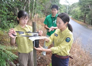 自動撮影装置を設置する岩本自然保護官（右）ら＝２２日、奄美市名瀬