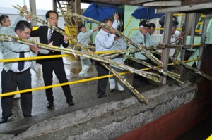 工場の圧搾機へと向かうコンベアーにサトウキビを投入する糖業関係者＝１日、沖永良部島の南栄糖業