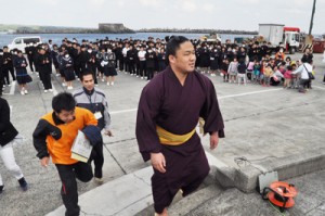 子どもたちに拍手で見送られ、船へと戻る石浦関＝１６日、和泊町手々知名の和泊港