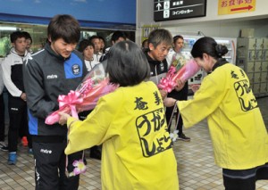 歓迎の花束を受け取る（右から）三浦監督と赤尾公選手＝１８日、奄美市笠利町の奄美空港