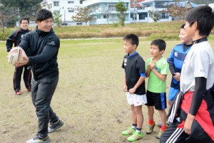 パスの動作を指導する重一生（左）＝１８日、奄美市の長浜緑地公園