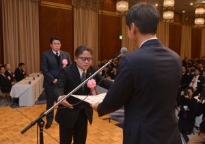 黒糖焼酎部門を代表して三反園知事から表彰状を受け取る西平本家の小畠社長＝１０日、鹿児島市のホテル