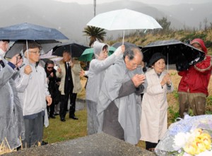 犠牲者を仮埋葬した海岸に手を合わせる対馬丸遺族団＝１８日、大和村