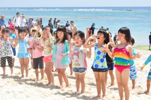 海開きイベントで、海をバックに浜辺でダンスを踊る園児ら＝２３日、知名町屋子母海岸