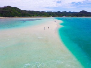 姿を現した「かくれ浜」を歩く観光客ら＝２６日午後１時２０分ごろ、奄美市笠利町の喜瀬沖（本社無人機で撮影）