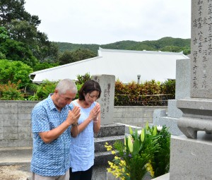 亡父の古里で墓前に手を合わせるフランクさん（左）と妻ダイアンさん＝２０日、瀬戸内町蘇刈  