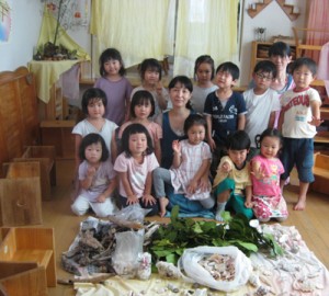 届いた「奄美箱」の品々を取り出した虹のこども園の園児ら（中央が虹乃園長）＝５日、宮城県仙台市（同園提供）