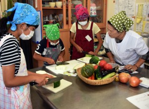 講師（右）のアドバイスに耳を傾けながら、材料の島野菜を調理する参加者＝２２日、奄美市笠利町