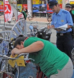 放置自転車にステッカーを取り付ける参加者＝２０日、奄美市