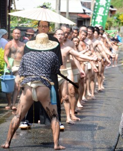 勇壮な掛け声を挙げながら集落内を練り歩く男衆＝１２日、宇検村芦検集落