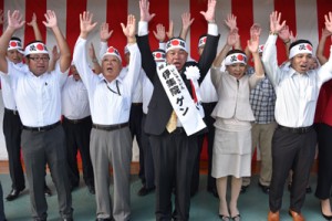 万歳三唱で三選を喜ぶ出陣式で３期目への決意を語る伊集院幼氏（前列中央）＝１５日、大和村大棚公民館