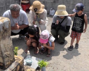 墓前に手を合わせて先祖の霊を迎える住民＝１３日、徳之島町亀津