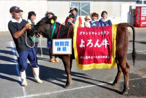 グランドチャンピオン牛「ひなた」と出品者の叶敏典さん（左）＝１６日、与論町