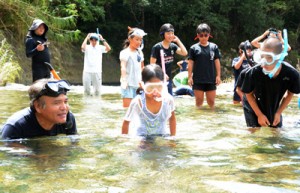 講師の興さん（左）とともに川の生き物を探す児童たち＝１９日、宇検村の河内川