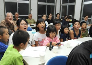 懸命に歌の練習をする子どもたち（上）と踊りの手本を見せる高齢者＝２２日、奄美市住用町の川内生活館