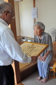 １００歳の長寿を祝う賞状を受け取る作田ハルさん＝１６日、伊仙町喜念