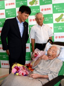 長寿世界一に認定される見通しの田島ナビさん（右）を訪問し、長寿を祝福する三反園訓知事（左）＝１８日、喜界町